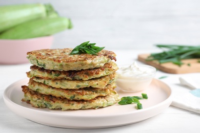 Delicious zucchini fritters served on white wooden table, closeup