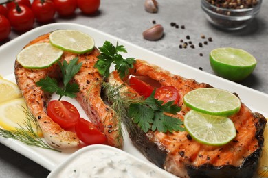Photo of Tasty grilled salmon steaks and ingredients on light grey table