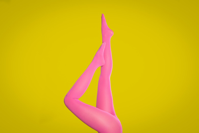 Photo of Woman wearing pink tights on yellow background, closeup of legs