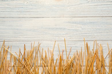 Dried hay on white wooden background, flat lay. Space for text