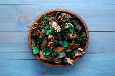 Photo of Aromatic potpourri of dried flowers in bowl on light blue wooden table, top view