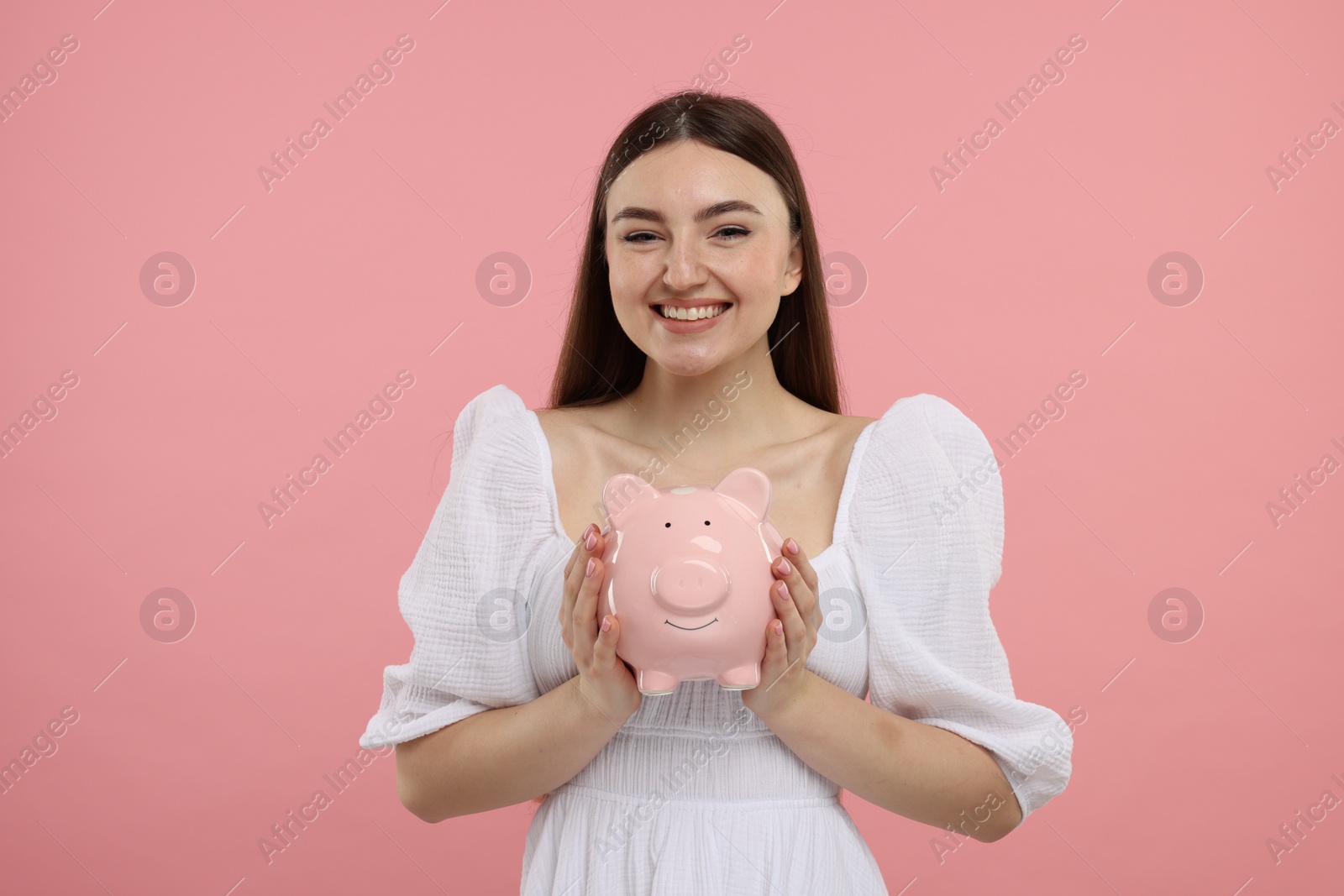 Photo of Happy woman with piggy bank on pink background