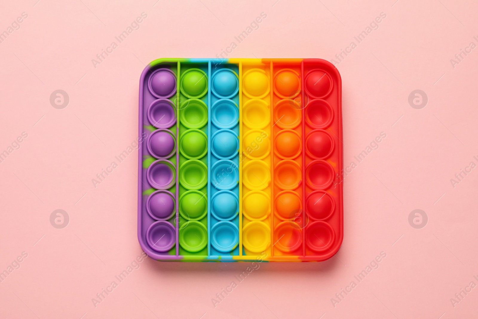 Photo of Rainbow pop it fidget toy on pink background, top view
