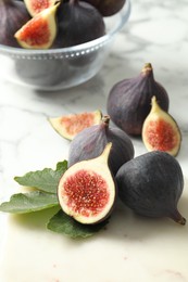 Whole and cut tasty fresh figs on white marble table