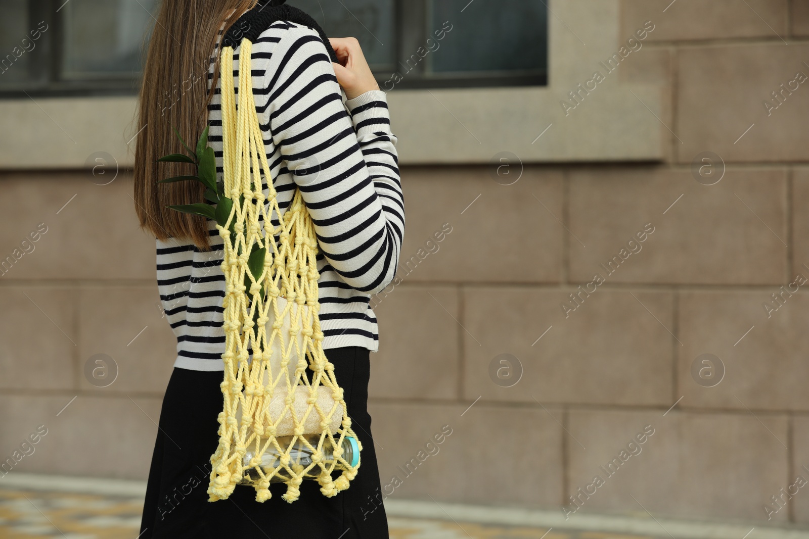 Photo of Conscious consumption. Woman with net bag of eco friendly products outdoors, closeup. Space for text