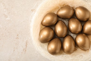 Photo of Golden eggs in nest on light table, top view. Space for text