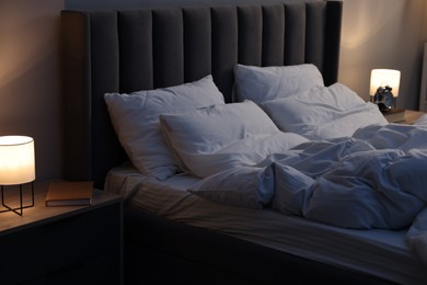 Photo of Soft bed and bedside table with nightlight indoors