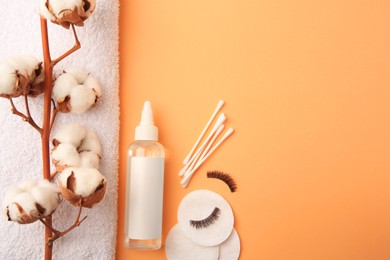 Photo of Flat lay composition with makeup remover and cotton flowers on pale orange background, space for text