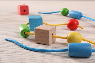 Wooden pieces and string for threading activity on light table, closeup. Motor skills development