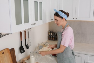 Smiling woman cooking in kitchen. Dirty dishware and utensils on messy countertop