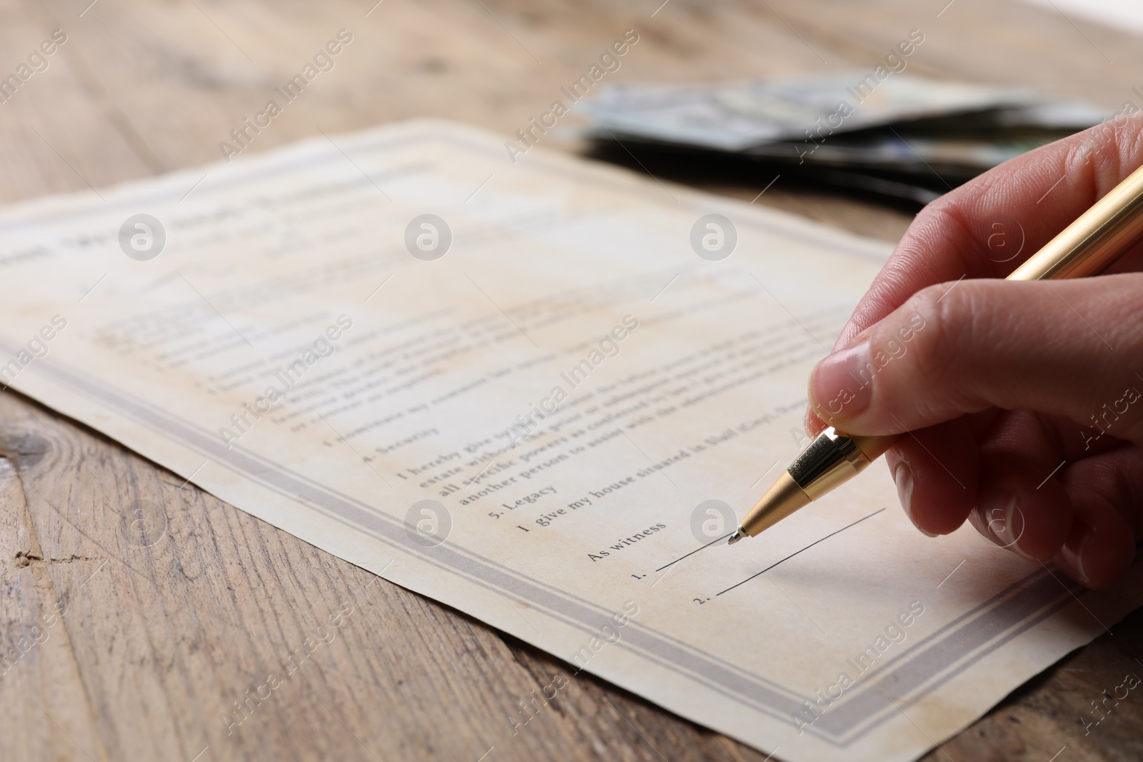 Photo of Woman signing Last Will and Testament at wooden table, closeup