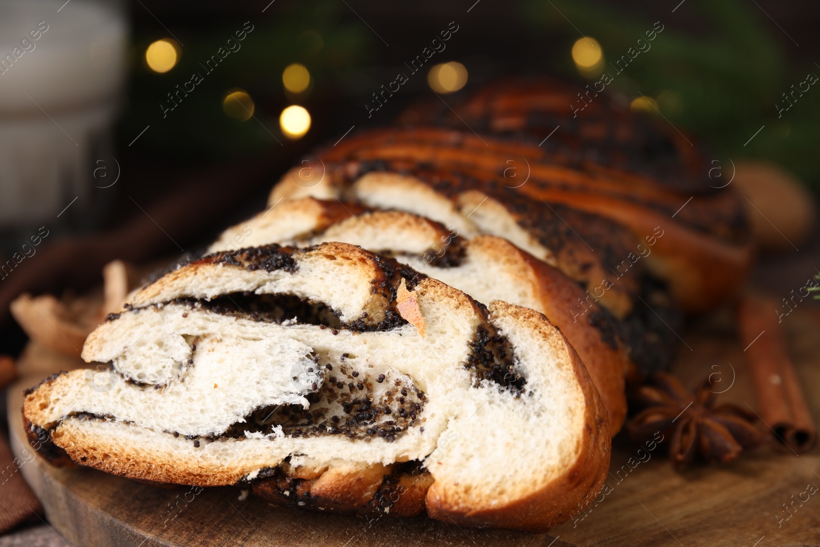 Photo of Cut poppy seed roll on wooden board, closeup. Tasty cake