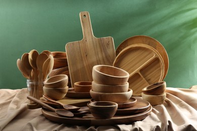 Set of wooden dishware and utensils on table against green background