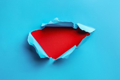 Photo of Hole in light blue paper on red background