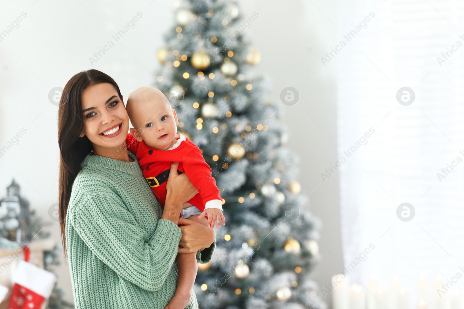 Photo of Mother with her cute baby at home, space for text. Christmas celebration