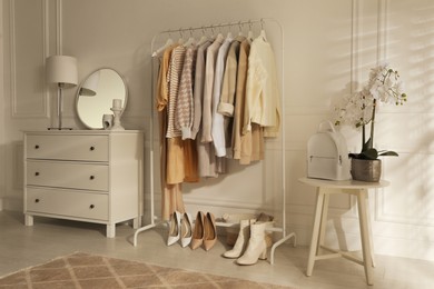 Modern dressing room interior with stylish clothes, shoes and beautiful orchid flowers