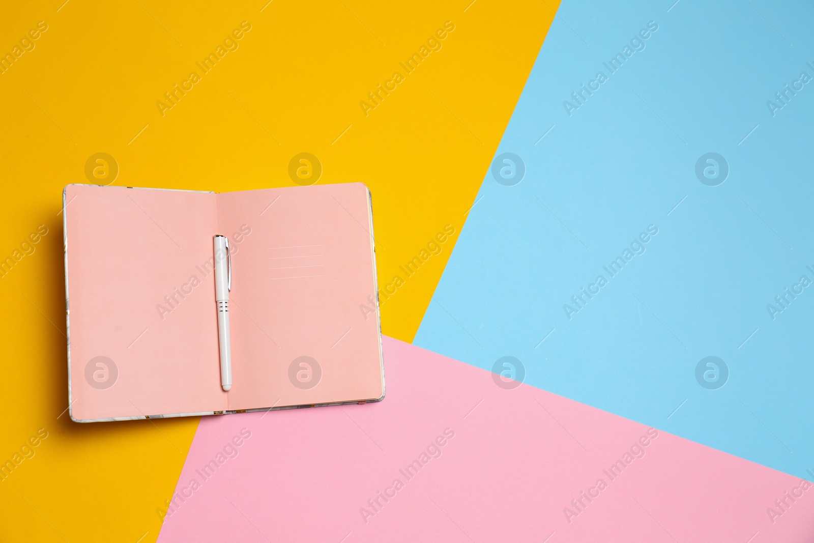 Photo of Notebook and pen on color background, top view. Space for text