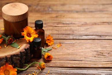 Photo of Different cosmetic products and beautiful calendula flowers on wooden table, space for text