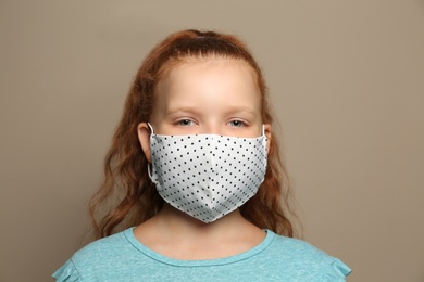 Photo of Preteen girl in protective face mask on brown background