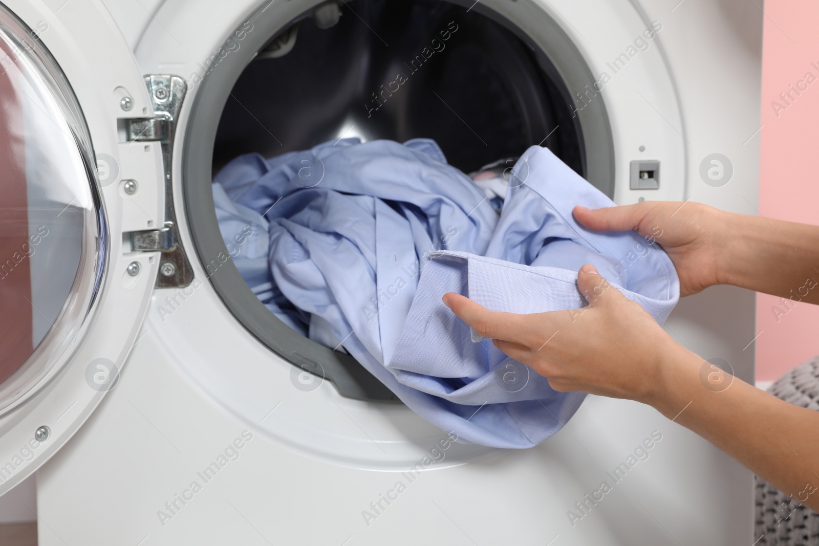 Photo of Woman taking laundry out of washing machine indoors, closeup