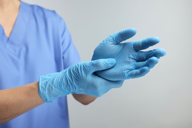Doctor wearing light blue medical gloves on grey background, closeup