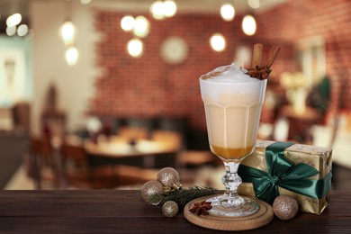 Image of Glass of delicious eggnog, Christmas ornaments, fir tree branch and gift box on wooden table in bar, space for text