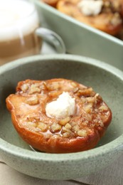 Photo of Tasty baked quince with cream cheese in bowl on table, closeup