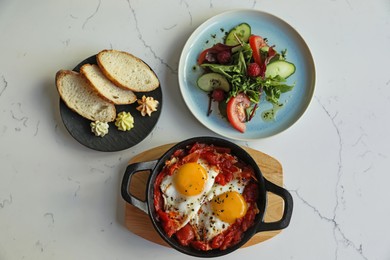 Tasty Shakshouka served on white marble table, flat lay