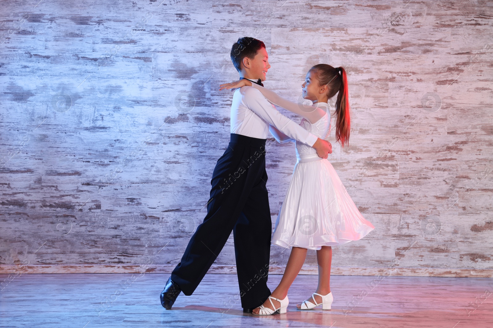 Photo of Beautifully dressed couple of kids dancing together in studio