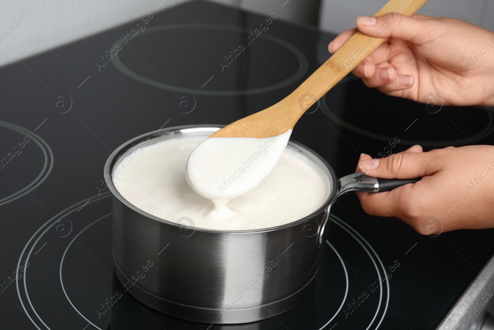 Photo of Woman cooking delicious creamy sauce in pan on stove, closeup