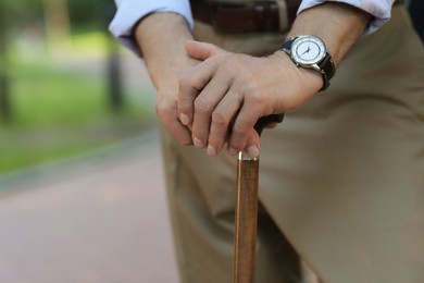 Senior man with walking cane outdoors, closeup