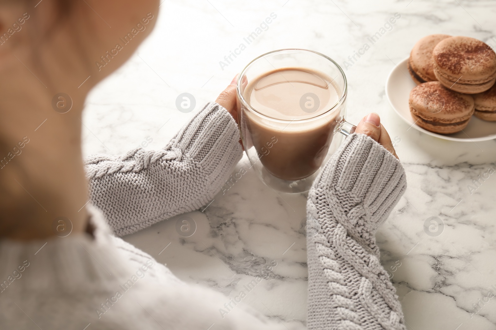 Photo of Young woman with delicious hot cocoa drink at table