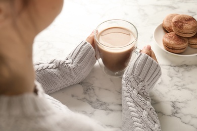 Young woman with delicious hot cocoa drink at table