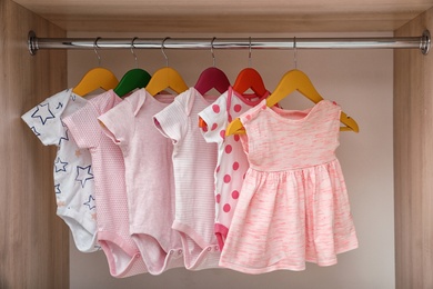 Photo of Hangers with baby clothes on rack in wardrobe