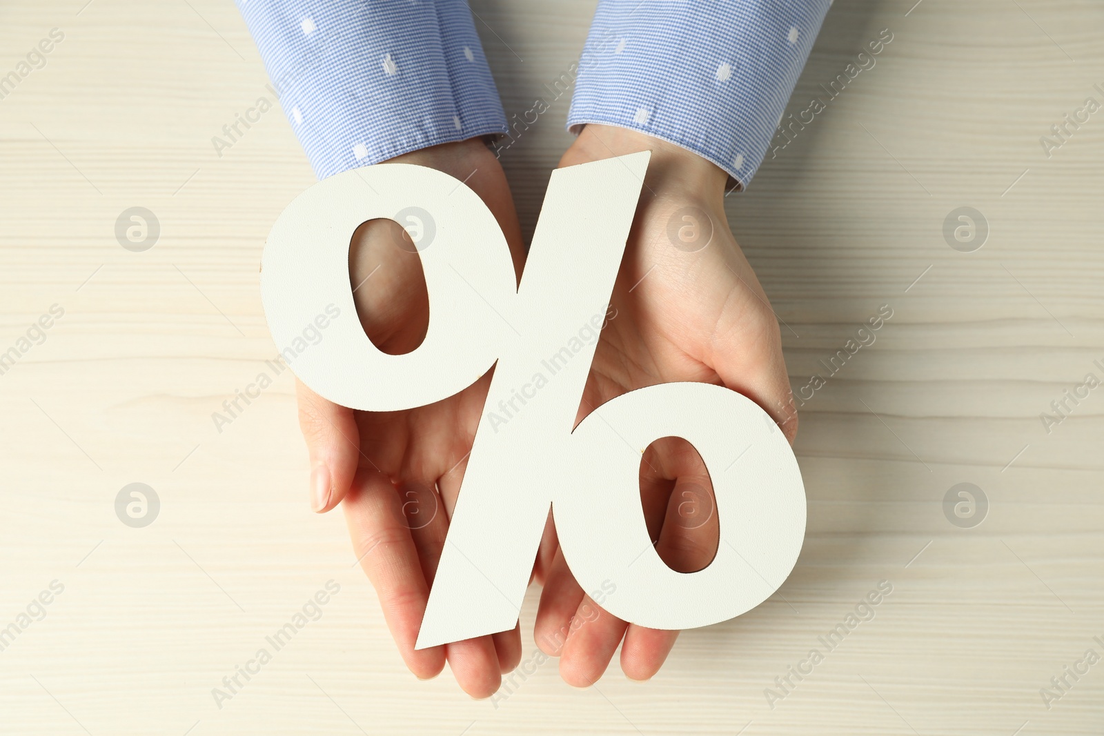 Photo of Woman holding percent sign at white wooden table, top view