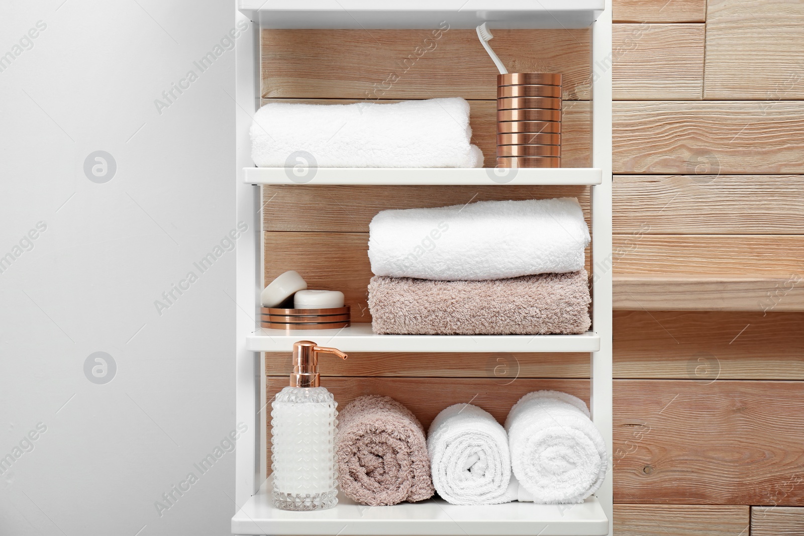 Photo of Towels, toiletries and soap dispenser on shelves in bathroom