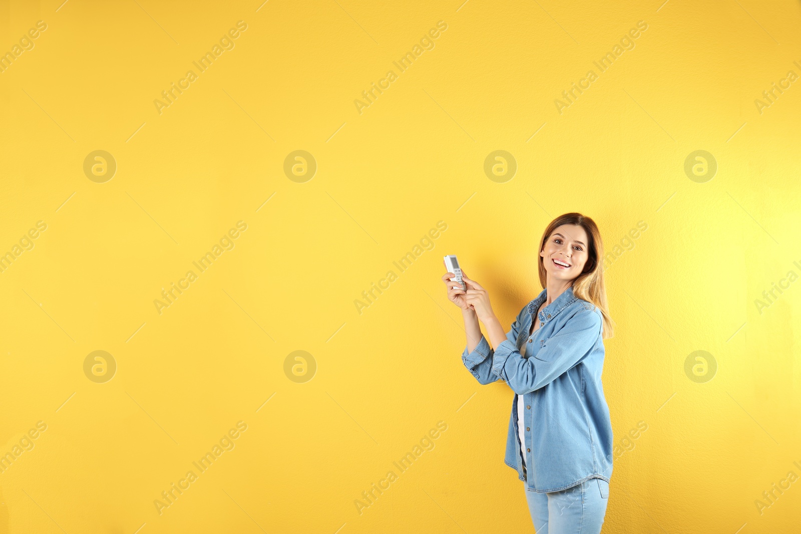 Photo of Woman with air conditioner remote on color background