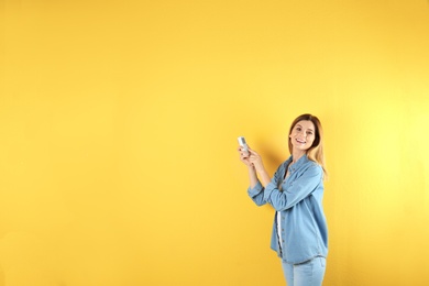 Woman with air conditioner remote on color background