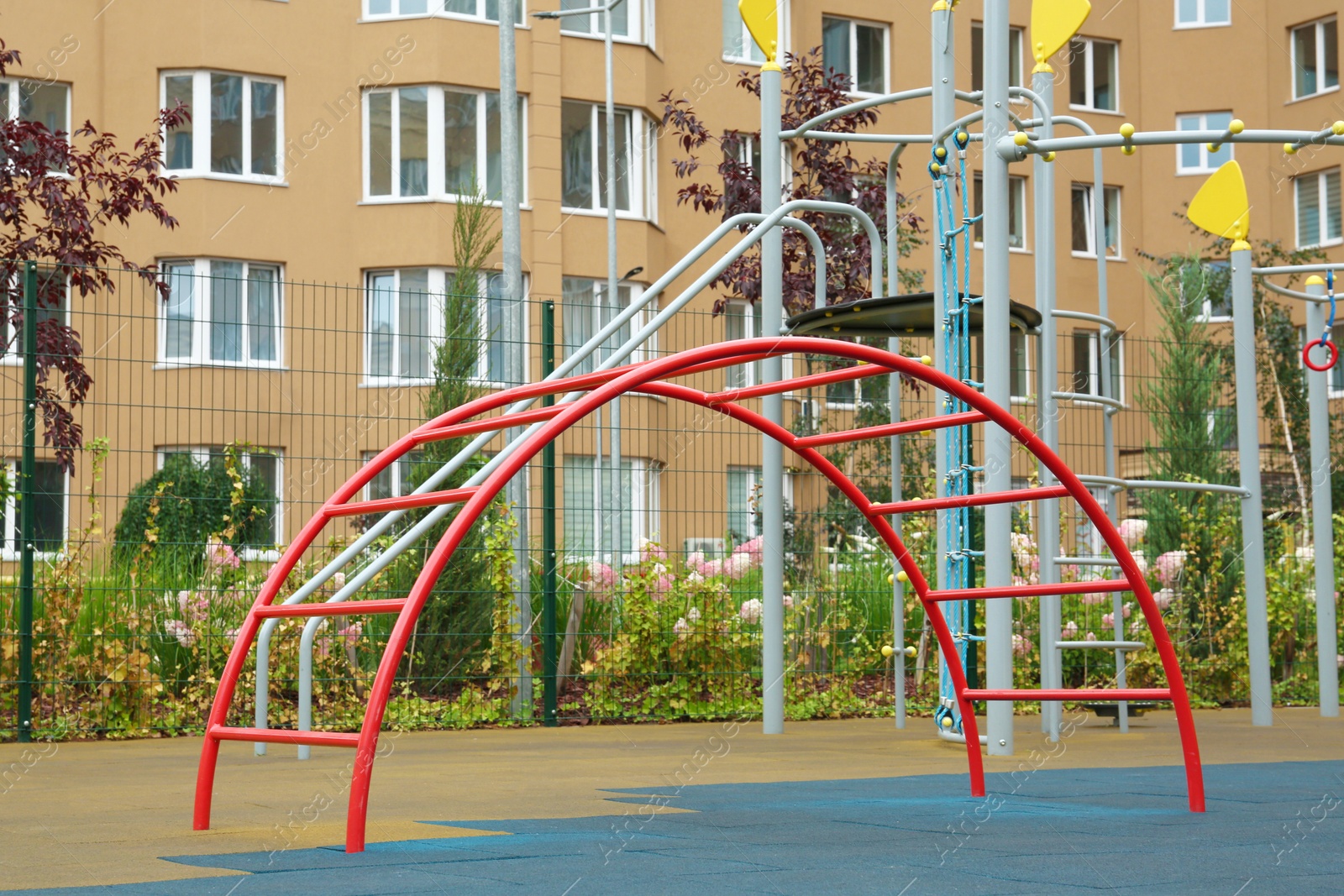 Photo of Red curved ladder on outdoor playground in residential area