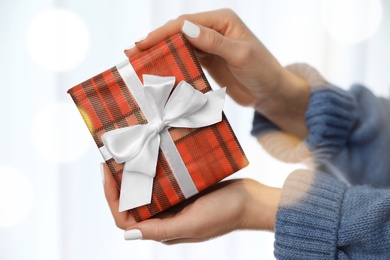 Photo of Woman in warm sweater holding Christmas gift on white background, closeup