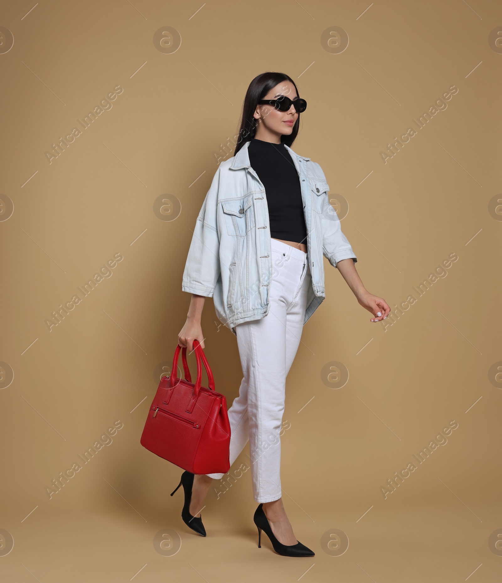 Photo of Young woman with stylish bag on beige background