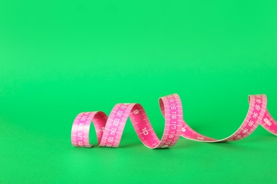 Photo of Pink measuring tape on green background, closeup