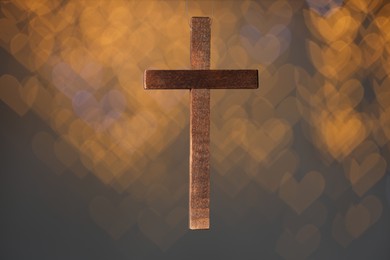 Photo of Wooden cross against blurred lights, closeup. Religion of Christianity