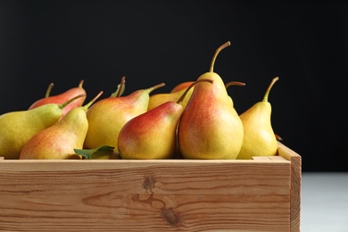 Photo of Wooden crate with ripe pears on black background, closeup