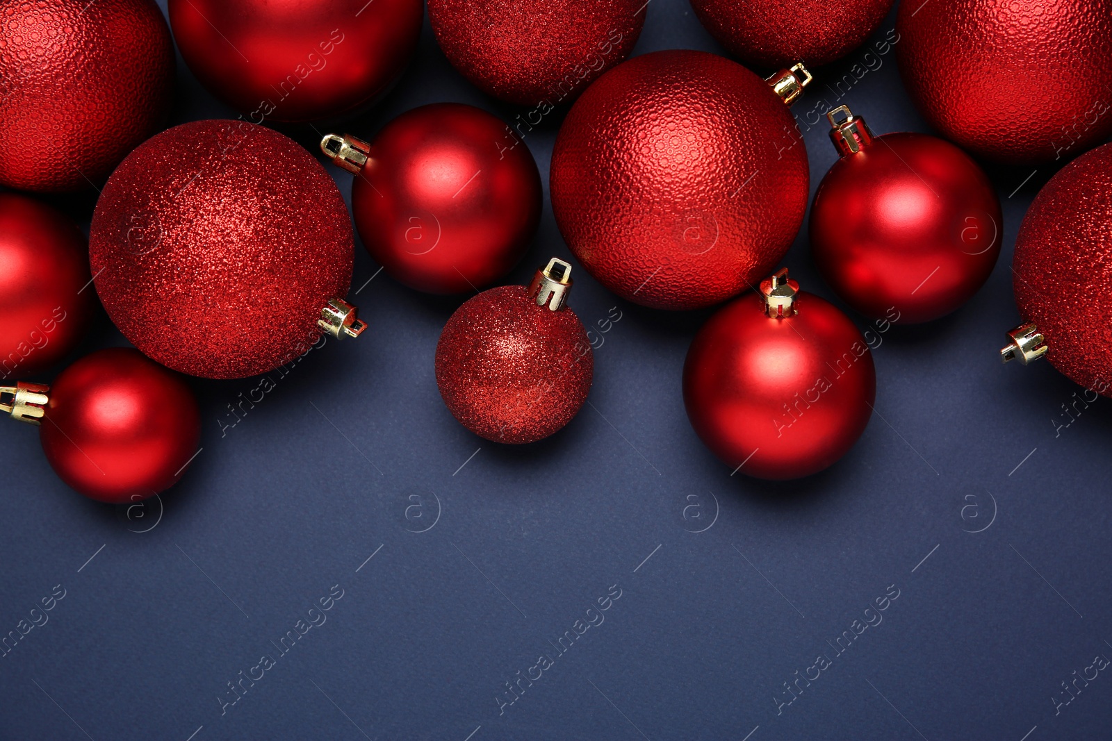 Photo of Red Christmas balls on dark blue background, top view. Space for text