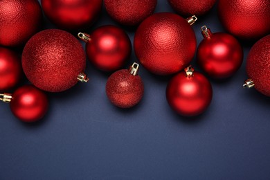 Photo of Red Christmas balls on dark blue background, top view. Space for text