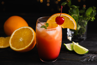 Photo of Fresh alcoholic Tequila Sunrise cocktail on black wooden table