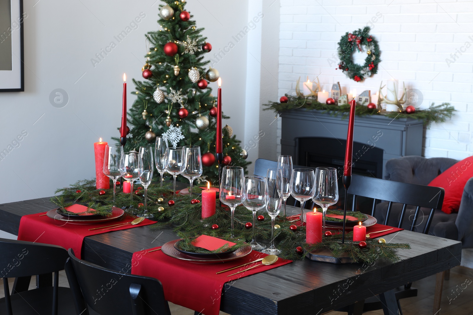 Photo of Elegant Christmas table setting with dishware and burning candles in festively decorated room