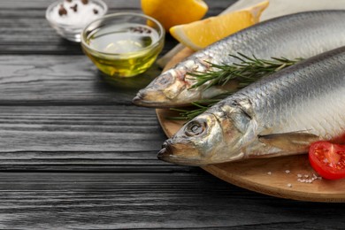 Photo of Delicious salted herrings and ingredients on black wooden table, closeup. Space for text