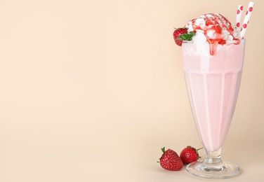 Photo of Tasty milk shake in glass and strawberries on beige background. Space for text
